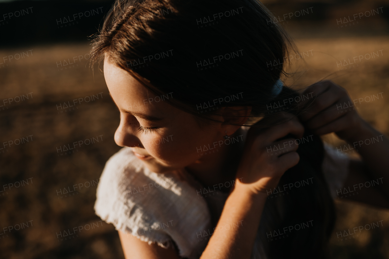 A portrait of a beautiful little girl in summer in nature during sunset.