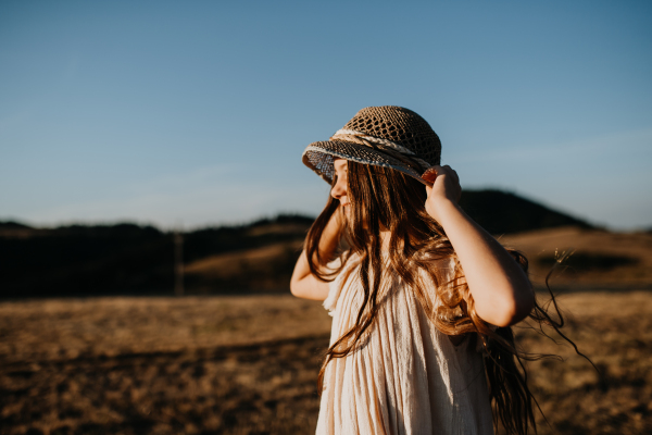 A portrait of a beautiful little girl in hat feeling free in summer in nature.