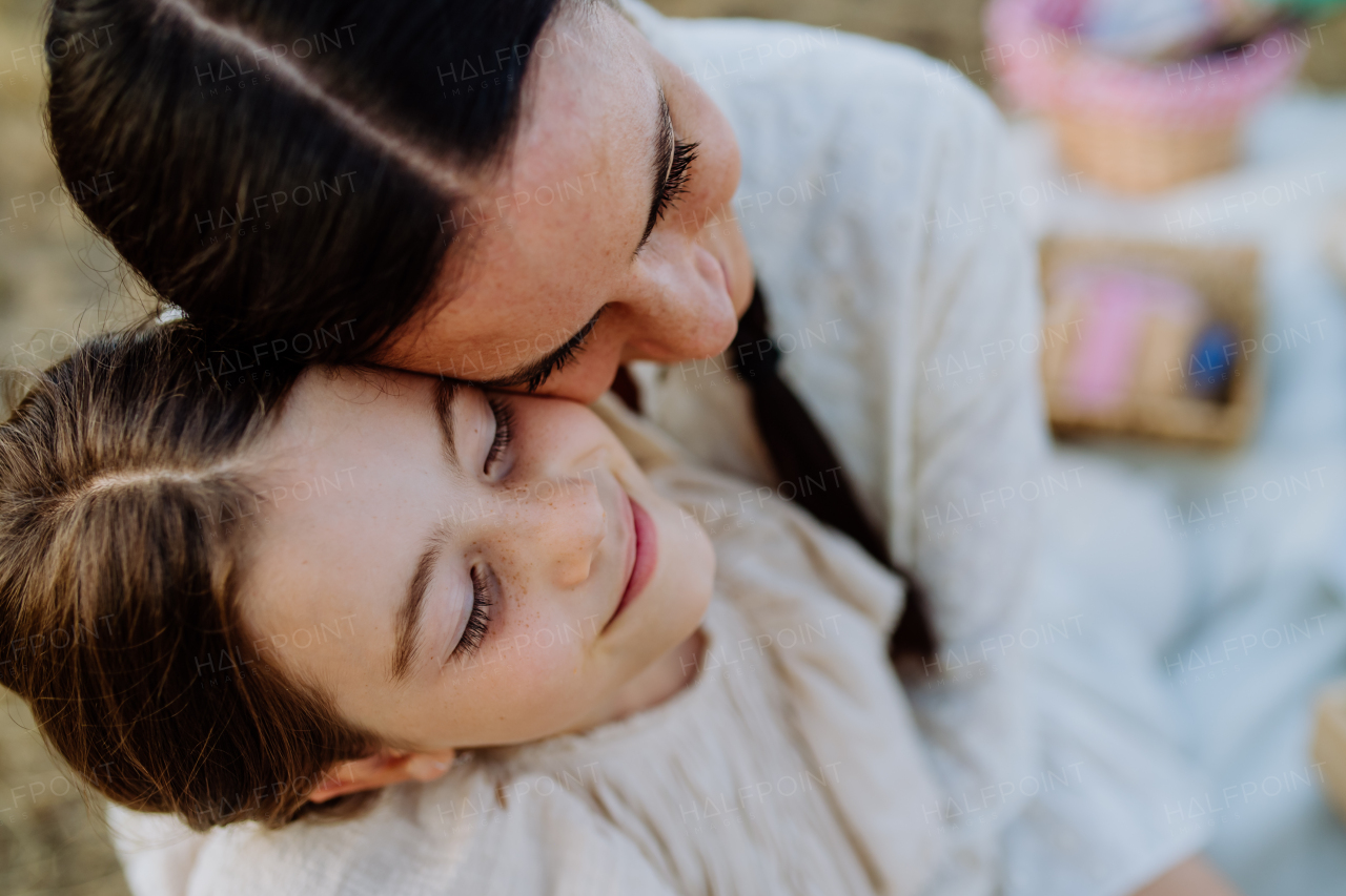 Happy, affectionate mother and daughter hugging during sunset.