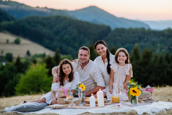 A portrait of happy family with children having picnic in nature in summer.