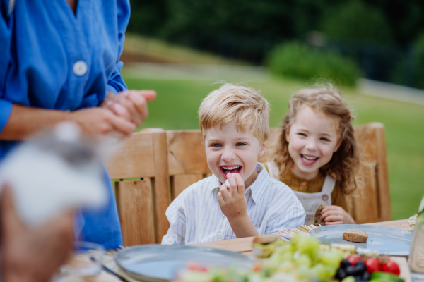 Happy kids enjoying the garden party with family, having fun and eating together.