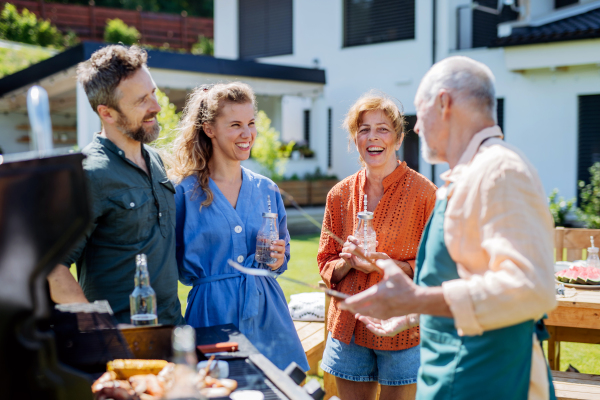 A multi generation family grilling outside on backyard in summer during garden party