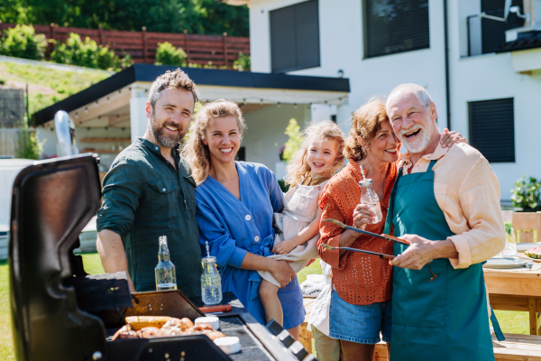 A multi generation family grilling outside on backyard in summer during garden party