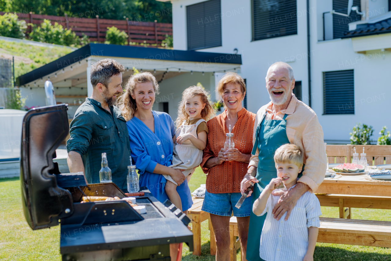 A multi generation family grilling outside on backyard in summer during garden party