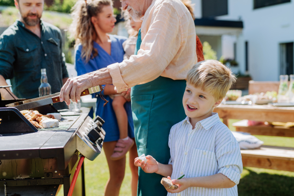 A multi generation family grilling outside on backyard in summer during garden party