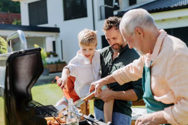 A multi generation family grilling outside on backyard in summer during garden party