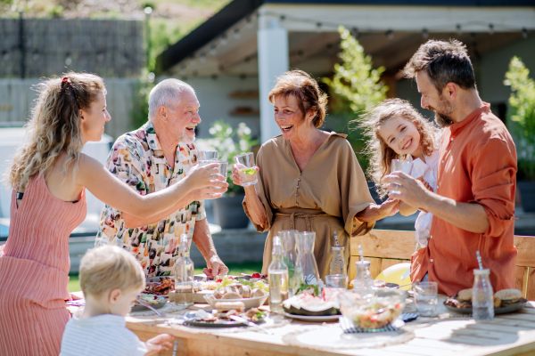 A multi generation family having garden party celebration, toasting and laughing.