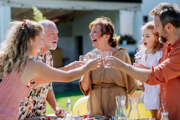 A multi generation family having garden party celebration, toasting and laughing.