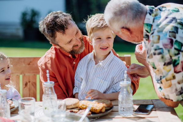 Multigenerational family having outdoor barbecue party in their backyard.