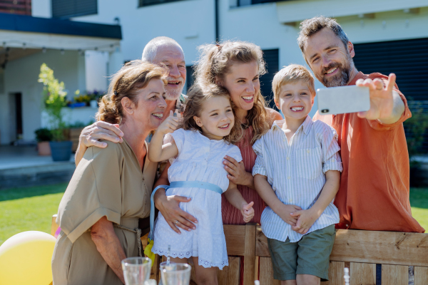 A multi generation family taking selfie on backyard in summer during garden party