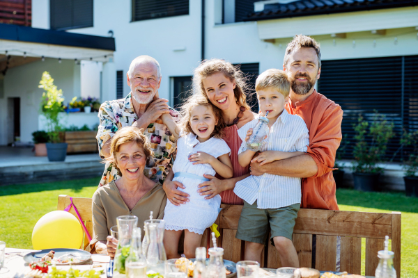 Multi generation family posing, taking photo on backyard in summer during a garden party.