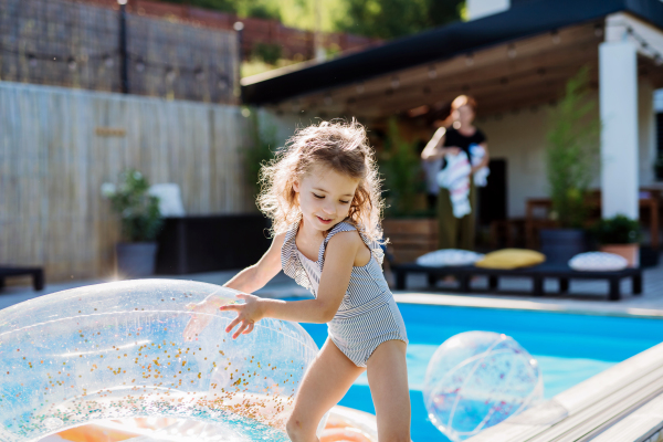 A happy kid having fun when running round the swimming pool with. Summer outdoor water activity for kids.