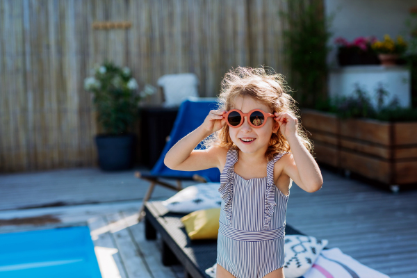 Portrait of a little girl in swimsuit with sunglasses.