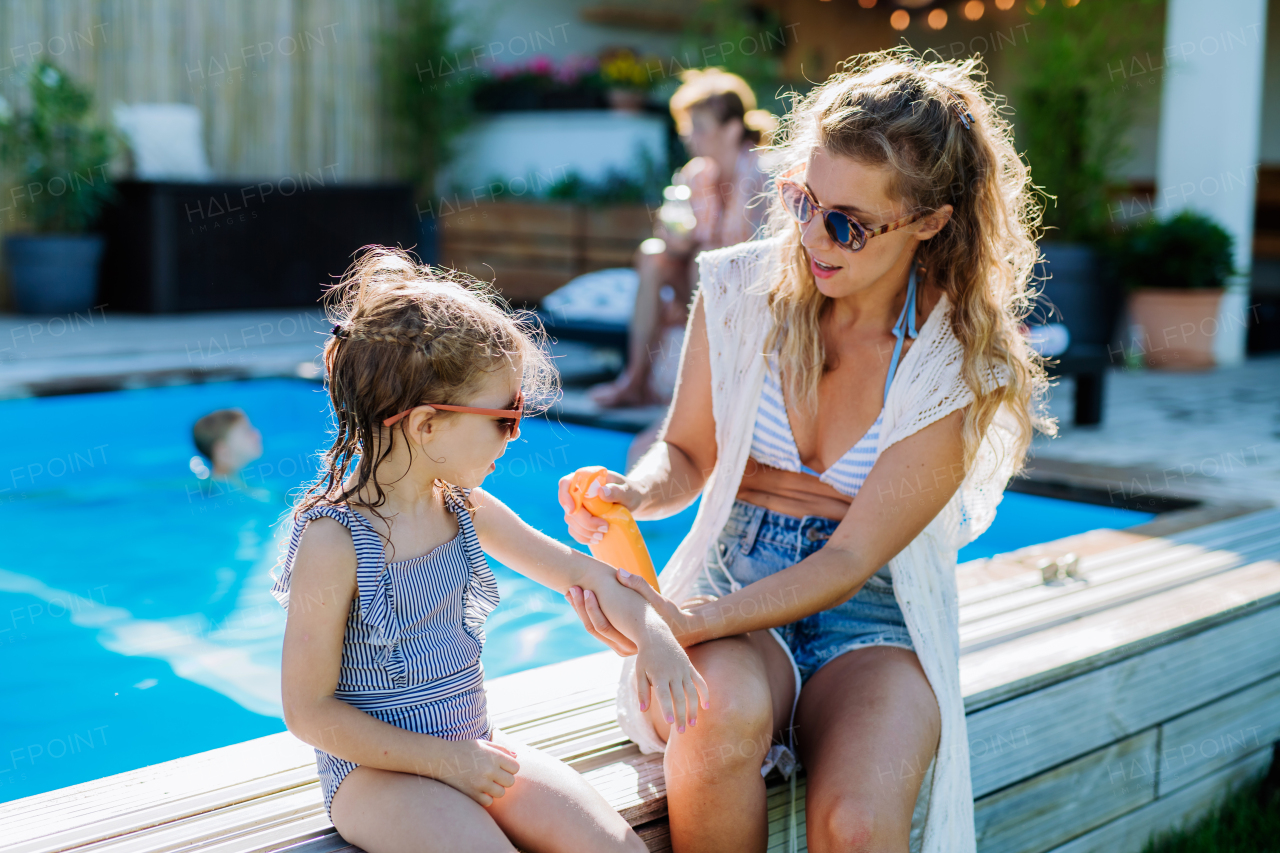 Young mother applying a sunscreen lotion to her daughter. Safety sunbathing in hot day.