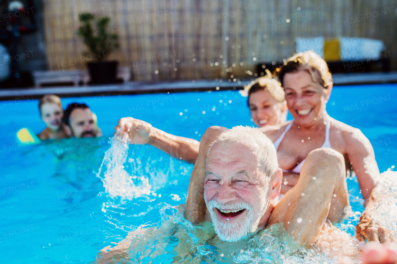 A multi generation family having fun and enjoying swimming in backyard pool.