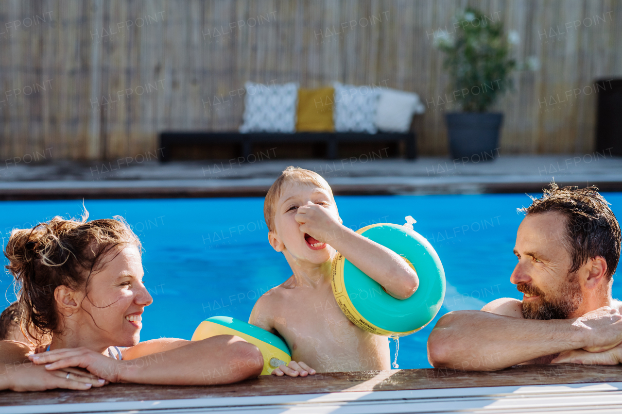 Happy young family spending summer time together in a pool.