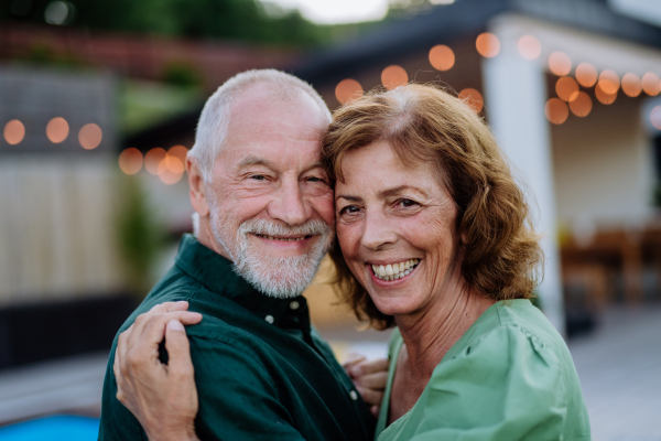 A senior woman nad man dancing and hugging together in a garden in summer