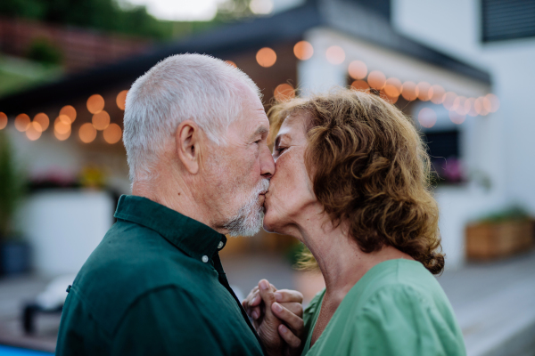 A senior woman and man kissing together in a garden in summer