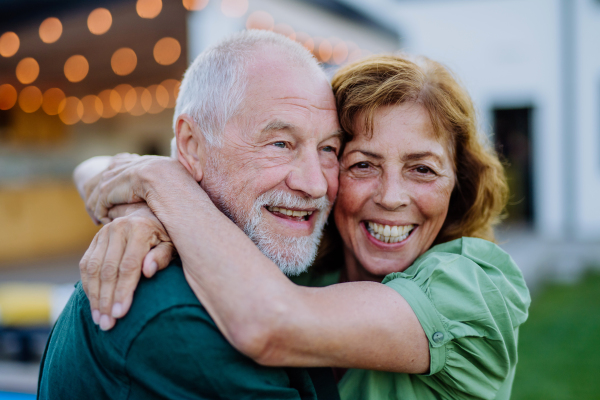 A senior woman nad man dancing and hugging together in a garden in summer