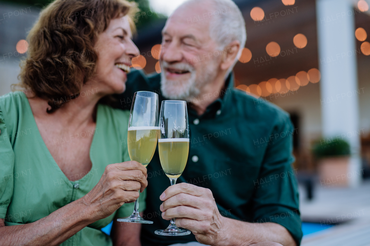 A man with his wife celebrating birthday and toasting with wine near backyard pool.