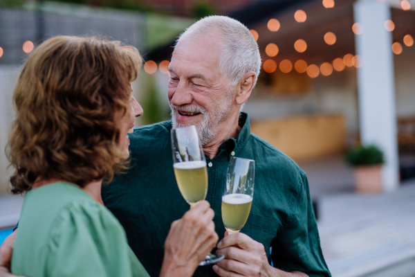 A man with his wife celebrating birthday and toasting with wine near backyard pool.