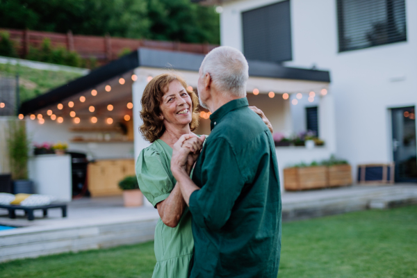 A senior woman nad man dancing together in a garden in summer