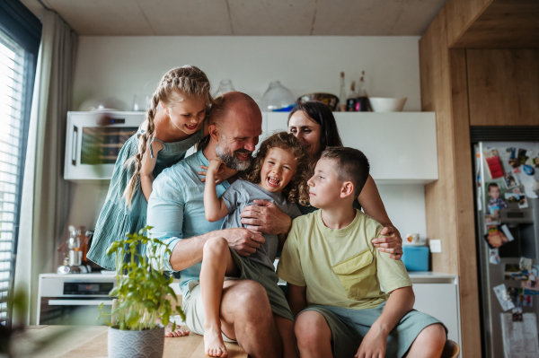 Cheerful family with three kids having fun together in kitchen. Concept of family bonding.