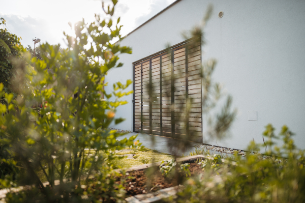 Modern house with beautifully landscaped home garden and wooden gate. Side, outdoor view of modern villa in the city.