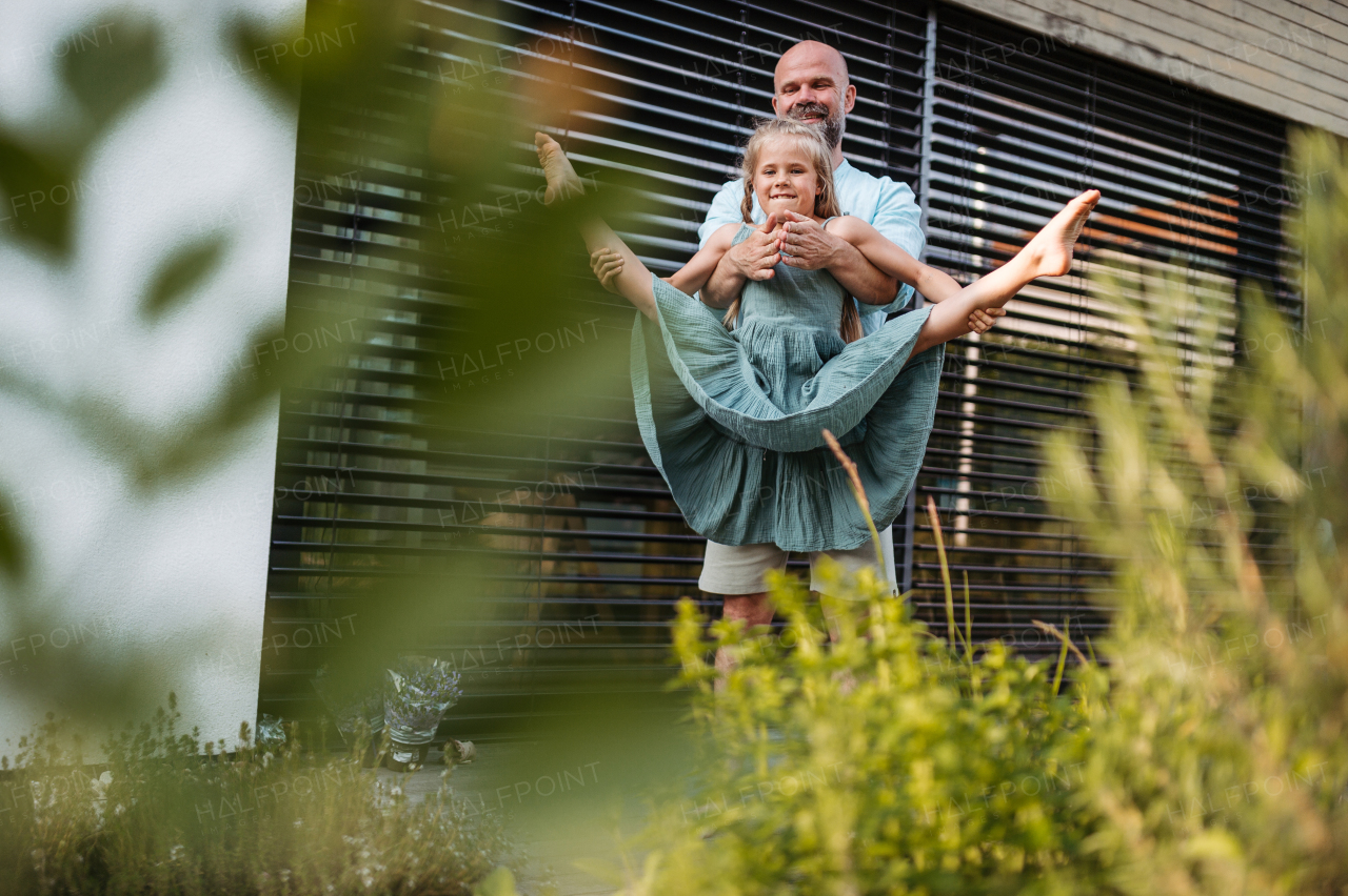 Father holding the daughter's waist, helping her jump higher. Young girl gymnast doing straddle jump.