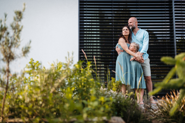 Portrait of a happy family spending time together outdoors. Mother and father holding daughte,r standing on terrace. Concept of family bonding.