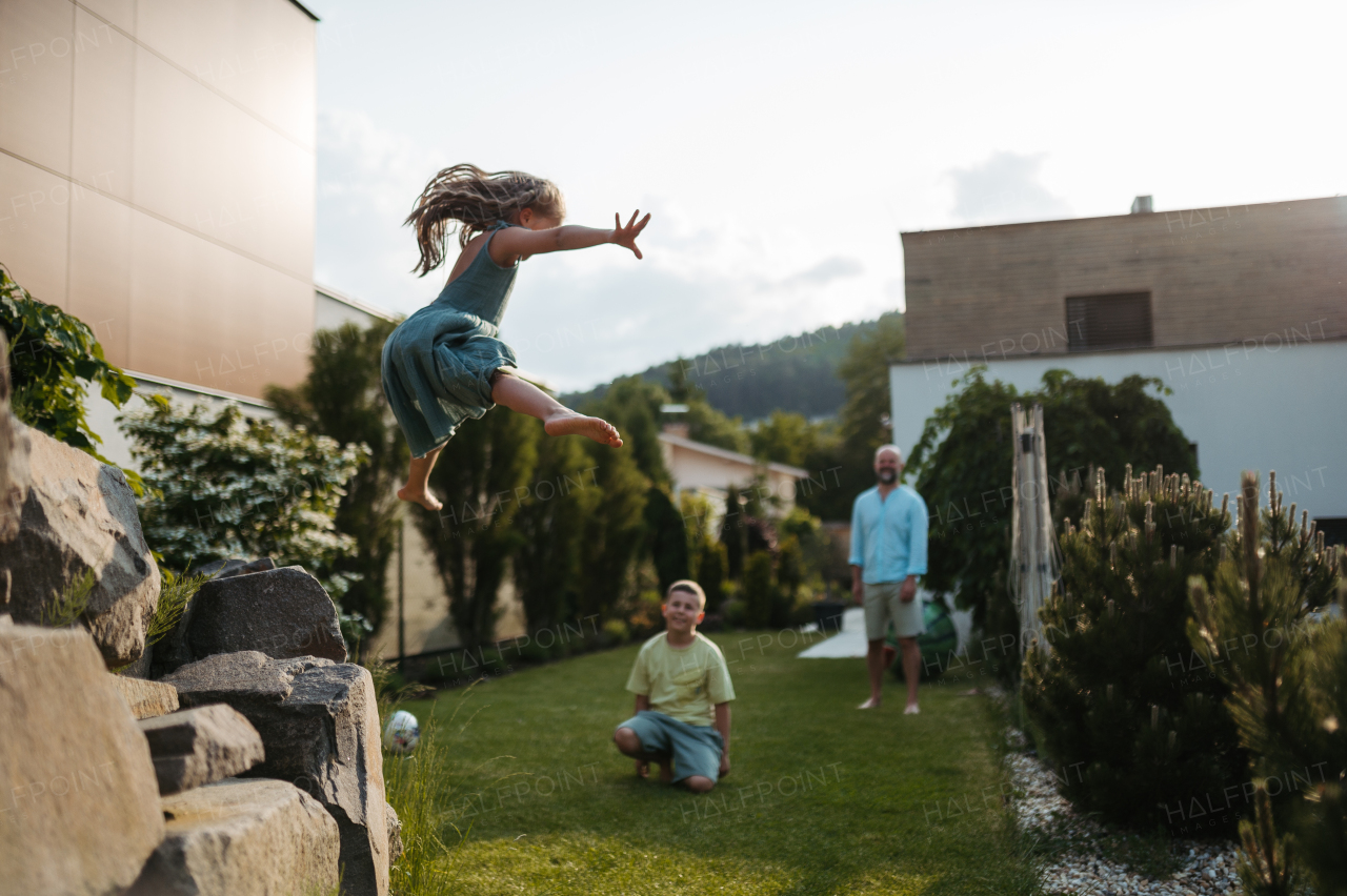 Father with two kids having fun together in the garden. Little girl jumping from the stone steps.