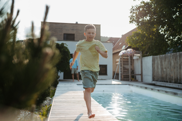 Young boy running along swimming pool at home. Pool safety with childrens.