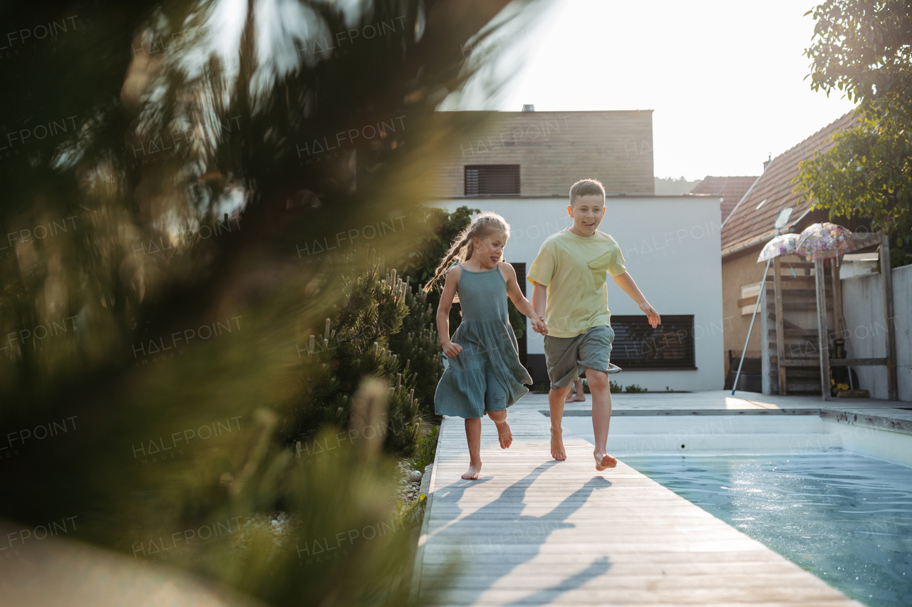 Young boy and little girl running along swimming pool at home. Pool safety with childrens.