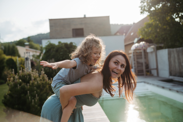 The mom is giving her little boy a piggyback ride in the garden. Bonding between mother and child, Concept of Mothers Day.