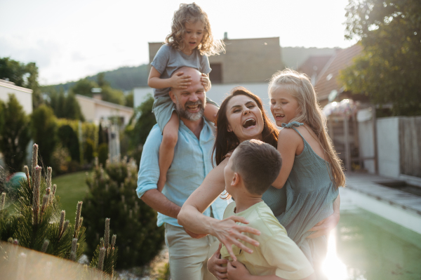 Portrait of cheerful family with three kids having fun together outdoors. Parents and kids embracing each other and laughing.