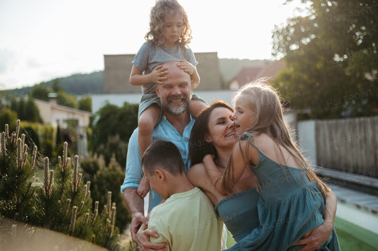 Portrait of cheerful family with three kids having fun together outdoors. Parents and kids embracing each other and laughing.