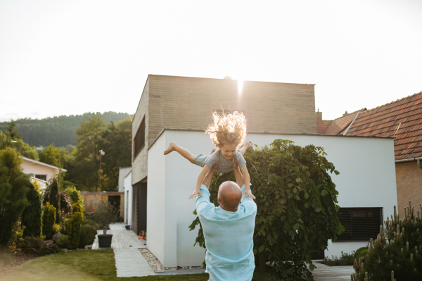 Father throwing little son up in the air in the garden. Dad with kid having fun outdoors. Father's day concept.