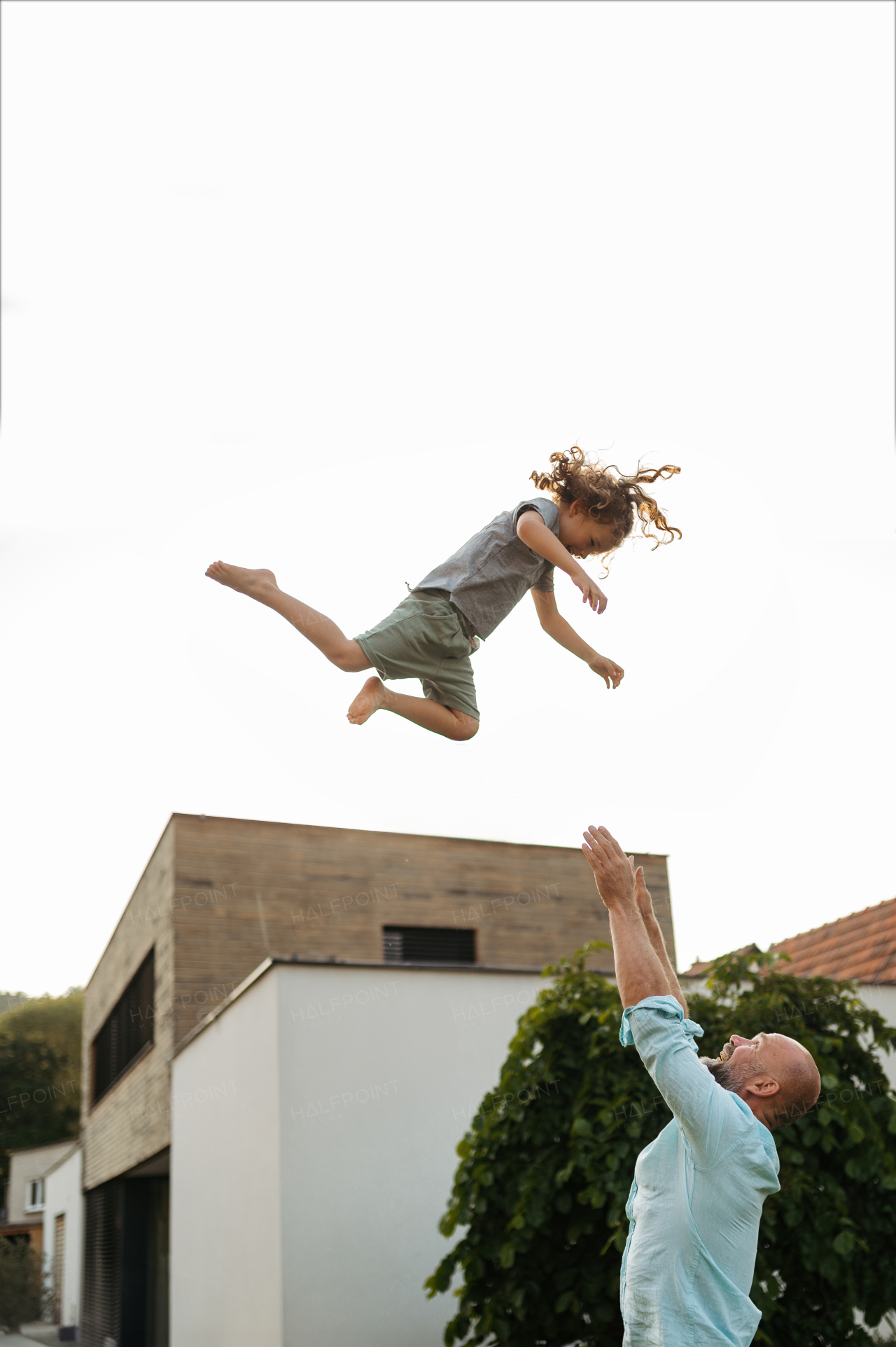 Father throwing little daugter up in the air in the garden. Dad with kid having fun outdoors. Father's day concept.