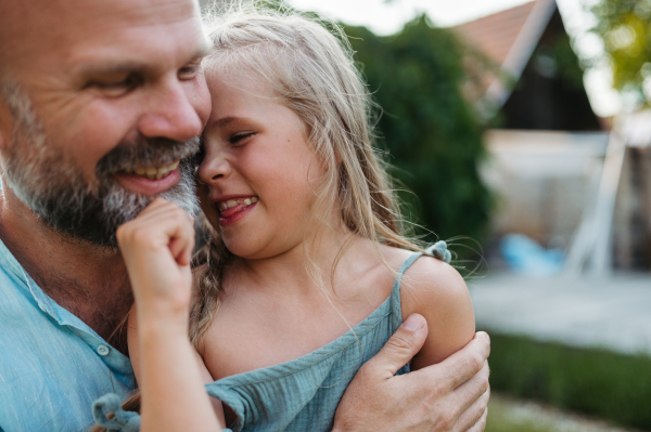 Portrait of father embracing his beautiful daughter in the garden. Dad and daughter spending quality time together, bonding.