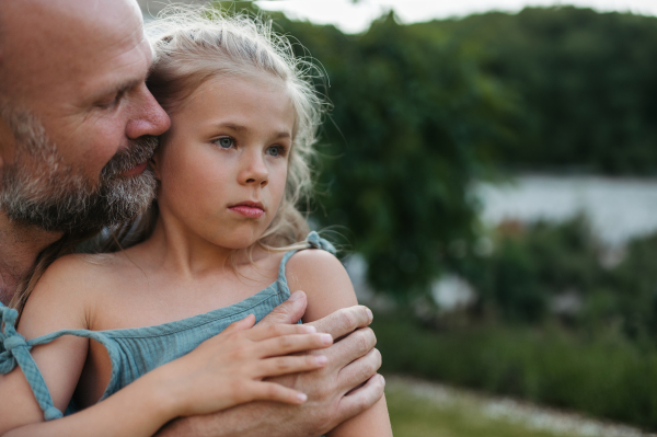 Portrait of father embracing his beautiful daughter in the garden. Dad and daughter spending quality time together, bonding.