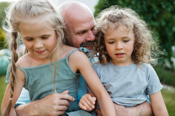 Portrait of father embracing his two beautiful daughters in the garden. Dad and daughter spending quality time together, bonding.