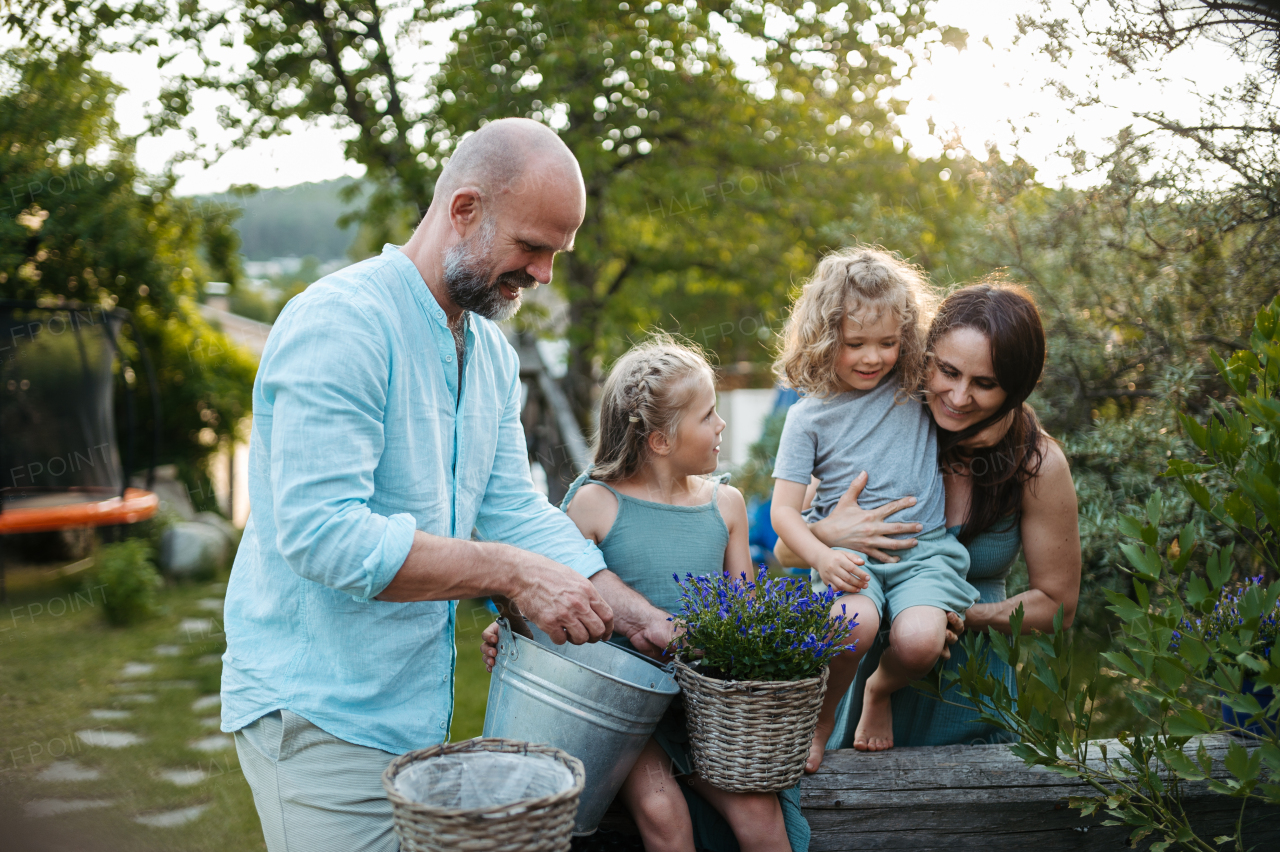 Happy family taking care of plants in the garden, trasnplanting flower to wicker flower pot. Concept of family bonding.