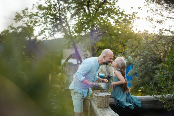 Father and daughter taking care of plants in the garden, trasnplanting flower to wicker flower pot. Dad and touching with noses.