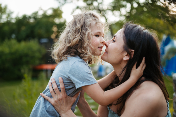 Portrait of mother embracing her beautiful son in the garden. Mom and daughter spending quality time together, bonding.