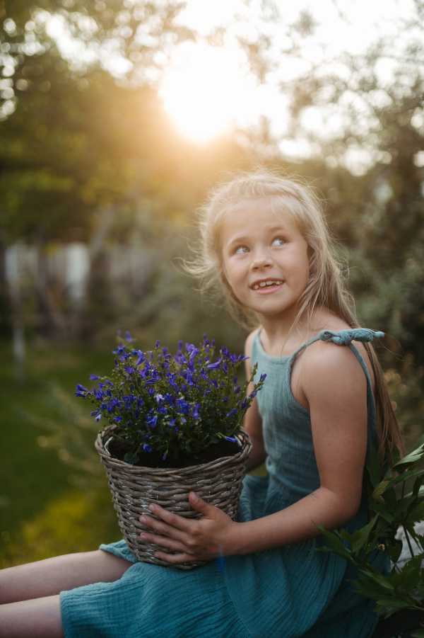 Potrait of little girl holding purple flower bells in pot.