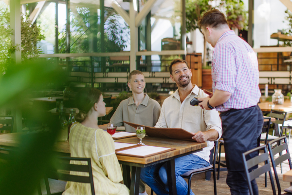 Father and children ordering food from a waiter. Single-parent family having dinner at a restaurant. Concept of Father's Day.