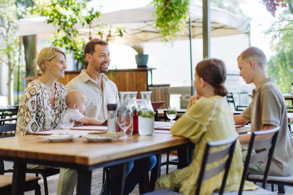 Big family with children and a small baby at family dinner in a restaurant. A small family celebration in family friendly restaurant.