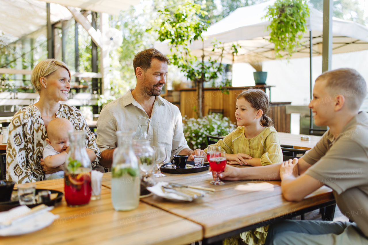 Big family with children and a small baby at family dinner in a restaurant. A small family celebration in family friendly restaurant.