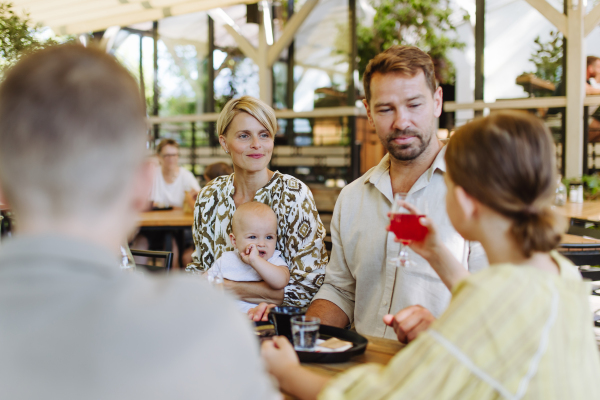 Big family with children and a small baby at family dinner in a restaurant. A small family celebration in family friendly restaurant.