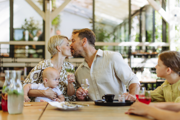 Family with daughter and a small baby at family dinner in a restaurant. A small family celebration in family friendly restaurant.